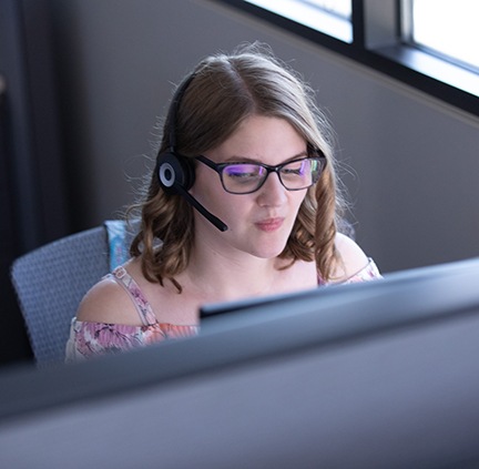 Alison sitting at the computer with her headset on 