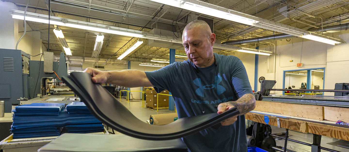 Man who is visually impaired prepares black foam material for products produced at Envision Dallas.