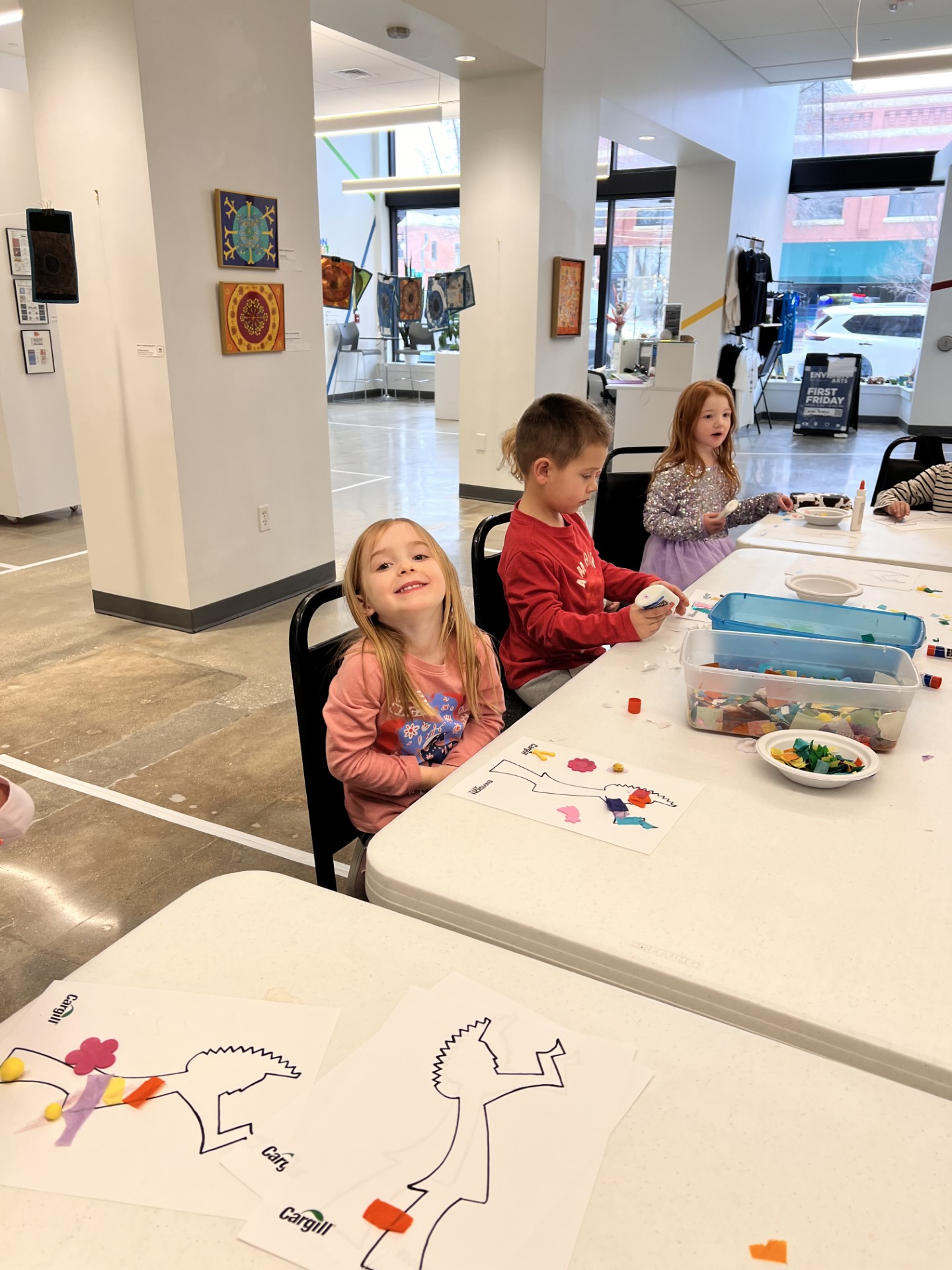 A young child at an art table smiling.