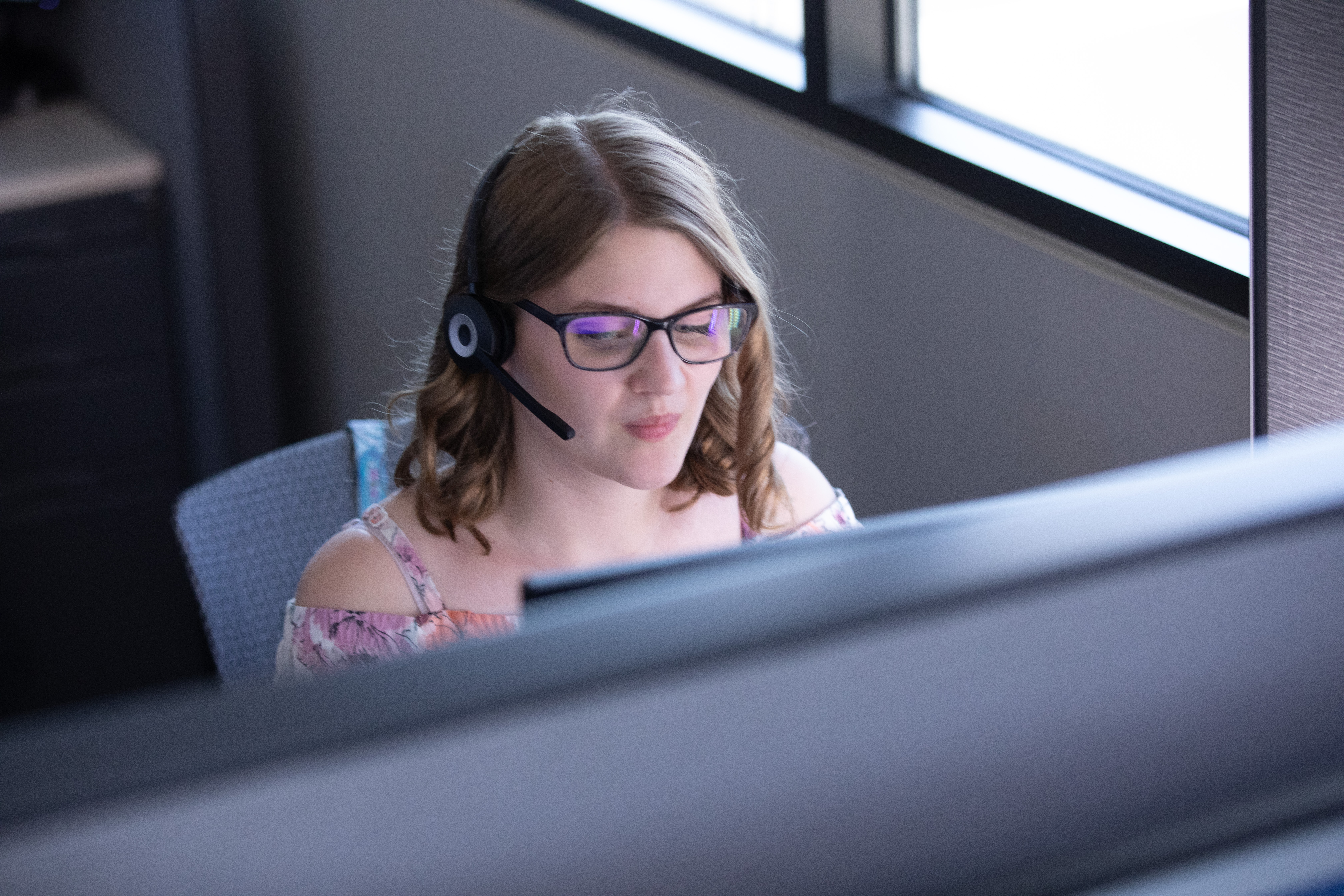 Alison Roets wearing her headset and sitting at the computer in WIC's call center